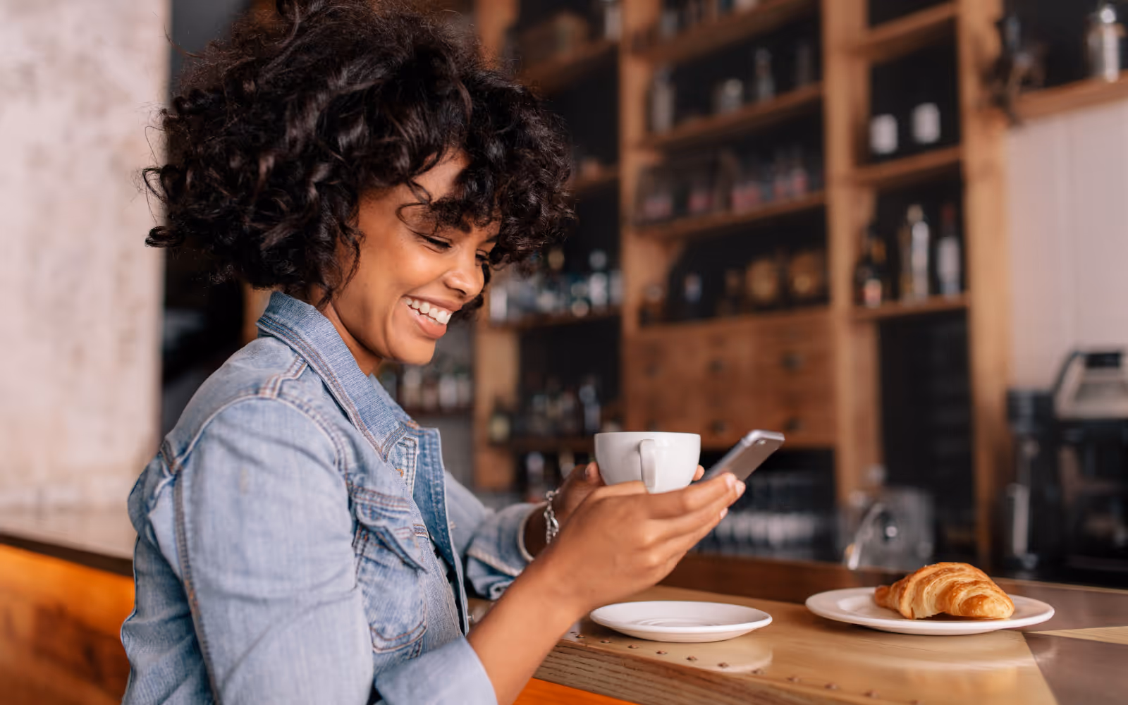 Person smiling looking at their phone in a coffee shop